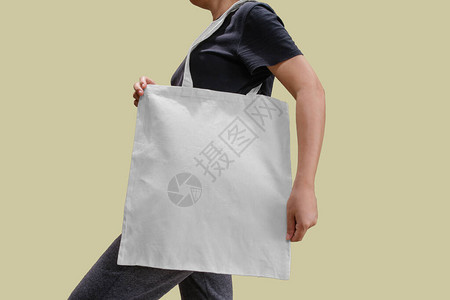 女手持可重复使用的白色棉麻生态有机织物手提袋隔离空白背景图片