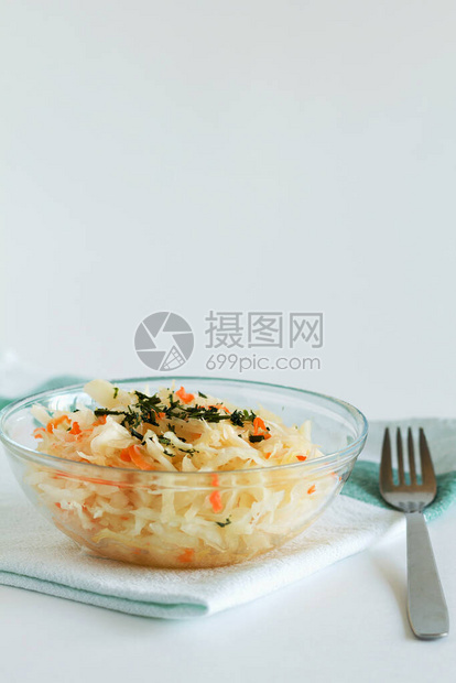 罐头食品的概念自制酸菜配胡萝卜和香草在白色背景上的玻璃盘子里用叉子和纺织品在桌子上的酸菜复制空间图片