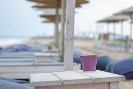 专注于海滩酒吧日光躺椅旁边木桌上的杯子海滩是图片