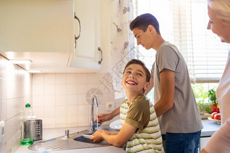两个男孩在厨房水槽洗碗图片