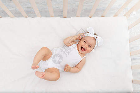 个月大的女婴躺在托儿所的婴儿床里图片