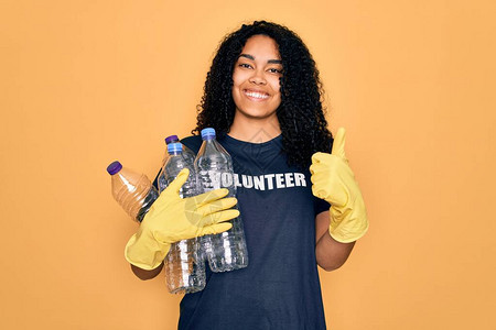 做志愿回收的年轻非洲裔美国女拿着塑料瓶开心地笑着做好手势图片