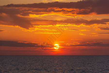 海上日落橙色的太阳特写在云层中美丽的日落海背景金色的云彩和巨图片