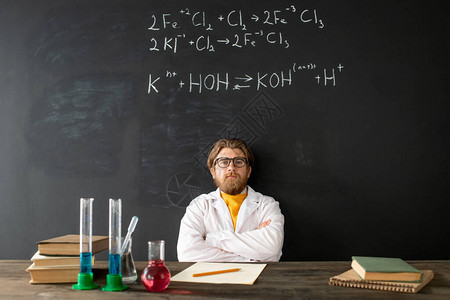身穿白大褂的当代年轻化学老师在网上课用化学公式对抗黑板时双图片