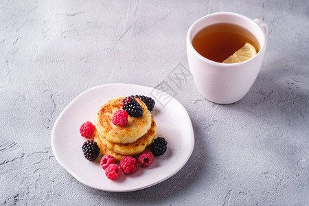 小屋奶酪煎饼凝乳油条甜点覆盆子和黑莓浆果放在盘子里图片