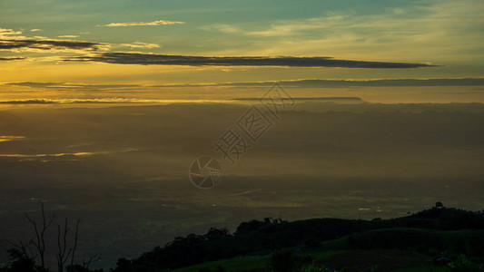 在山谷的地平线上与光日出景观的视图在雾山的明亮的图片