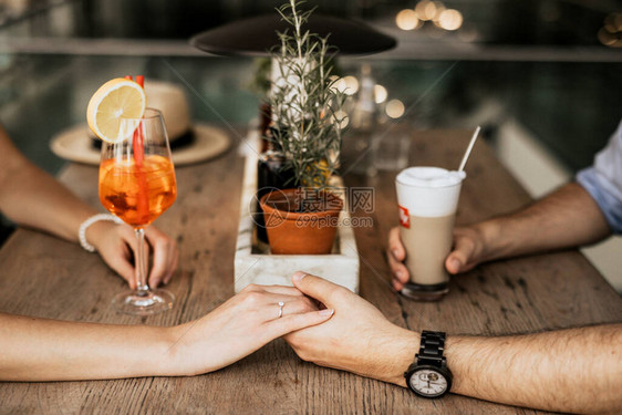 幸福的一对小情侣手握在桌子上在休息图片