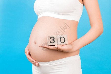 关闭穿着白色内衣的孕妇拿着带有怀孕周数的立方体怀孕三十图片