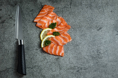 用刀切开新鲜生鲑鱼沙西米和柠檬图片