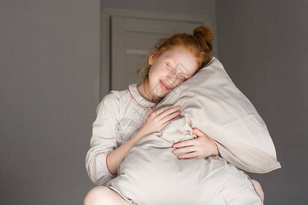 红发女孩睡眼惺忪地抱着枕头图片