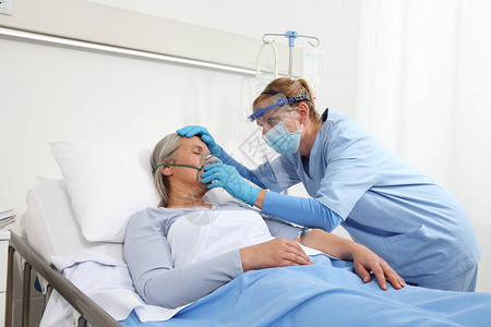 护士给躺在病房床上的老年妇女戴上氧气面罩图片