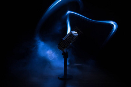 用于音频工作室或舞台的声音乐卡拉OK的麦克风麦克风技术语音广播设备带背光的桌子上的黑暗房间里的麦克风图片