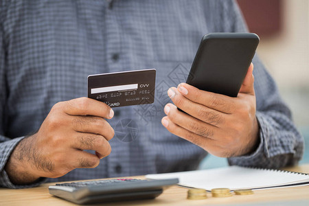 关闭商人手拿着信用卡和使用智能手机到财务管理网上购物图片