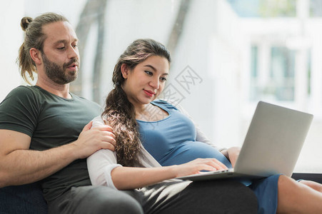 胡子人和他的怀孕妻子在看笔记本电脑上的电影图片