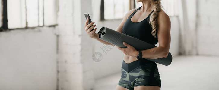 运动服部的肌肉中年妇女持垫子图片
