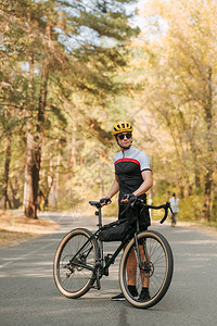 穿着运动服的骑自行车者在秋季森林的路上摆姿势拍照图片