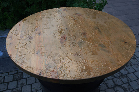 雨后在街头咖啡厅的木制桌顶上的一对木制桌子上图片