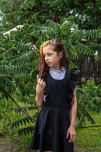 站在雨中的湿女学生女孩湿了在春天或温暖的秋天穿着校服的少年五年级的女孩染发一名女学生溅起水花的肖图片