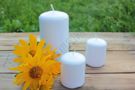 夏日花园木桌上的白蜡烛和黄花图片