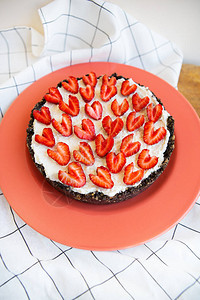 用心形草莓装饰的草莓芝士蛋糕放在珊瑚色的盘子上图片