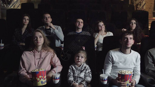 年轻人坐在电影院看电影吃爆米花友谊和图片