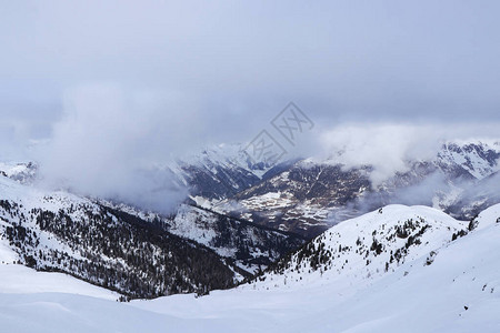 在奥地利西部蒂罗尔的奥地利阿尔卑斯山之间的白雪皑的Villgratental山谷的视图这些2000米高的山峰迷失在浓雾和厚云中滑图片