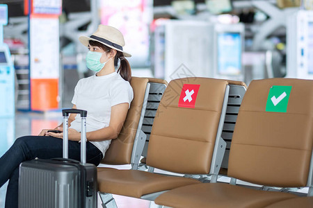 年轻女戴面罩坐在机场椅子上图片