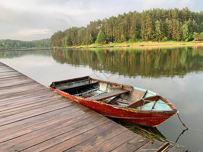 在湖的背景上的码头上的木船在森林水库岸边的渔船系在岸边概念图片