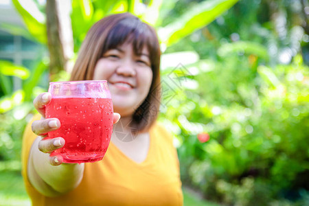 亚洲胖女人拿着一杯红花蜜吃了很多不利于健康容易导致肥胖图片