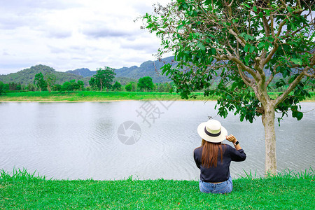 女人戴着帽子坐在大湖边图片
