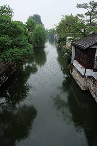 浙江南浔古镇旧式房子和绿树沿着宁静的河流与反射图片