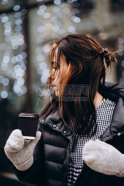 一位戴着手套和羽绒服的年轻美女手里拿着一杯次咖啡图片