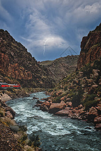 当火车引擎在峡谷或峡谷科罗拉多州的度假和旅行中沿河行驶时图片