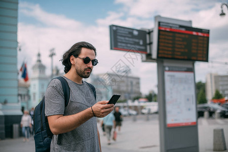 一个男人在车站看火车时刻表的电话图片