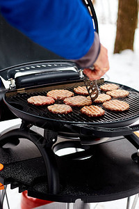 男人在便携BBQ上烤牛排寒冷的雪冬图片