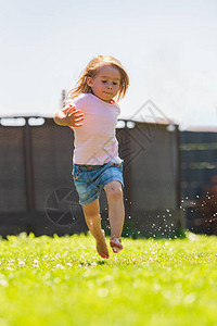 快乐的孩子跑过湿草坪泼溅的水童年概念图片