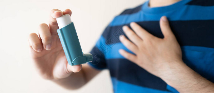 年轻人使用蓝色哮喘吸入器缓解哮喘发作医药产品用于预防和治疗由哮喘或慢阻塞肺病引起的喘息和呼吸急促保背景图片