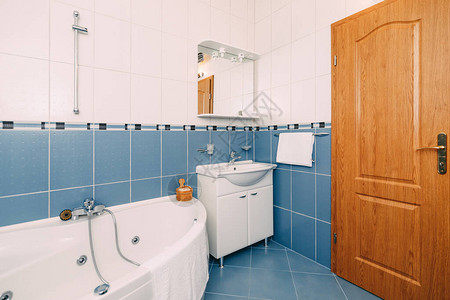 带水力按摩浴缸的浴室带镜子的洗脸盆和棕色木门高品质照片图片