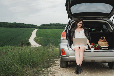 年轻时尚女坐在她的SUV汽车的轮架上图片