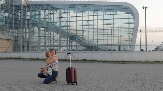 女人张开双臂在机场航站楼附近遇见她的小女儿期待已久的会议快乐的母女在长途飞行假期旅行工作后图片