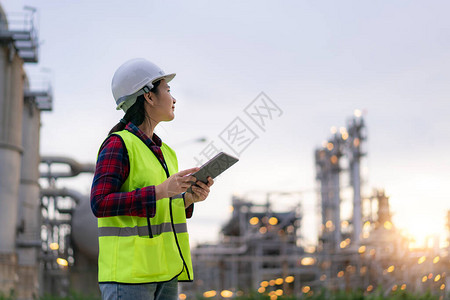 亚洲女石化工程师与数字平板电脑在石油和天然气炼油厂工业厂内进行检查员图片
