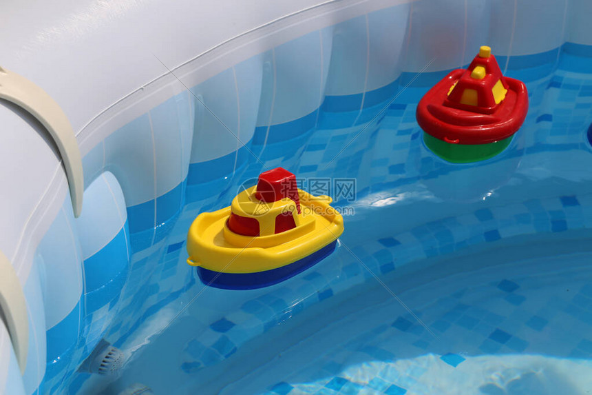 色彩鲜艳的玩具船漂浮在家庭游泳池中图片