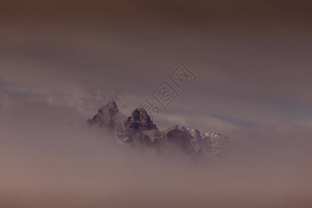 黎明时多洛米特山峰在云中偷窥图片