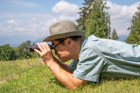 一位躺在草地上使用望远镜的男子的侧视线图片