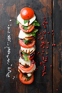 以西红柿马扎里拉绿色烤肉在旧厨房桌子上垂直切开的新鲜意大利羊毛图片