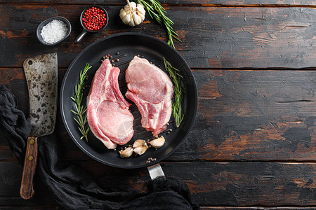 在质朴的木制餐桌上用煎锅烤生猪肉排骨图片
