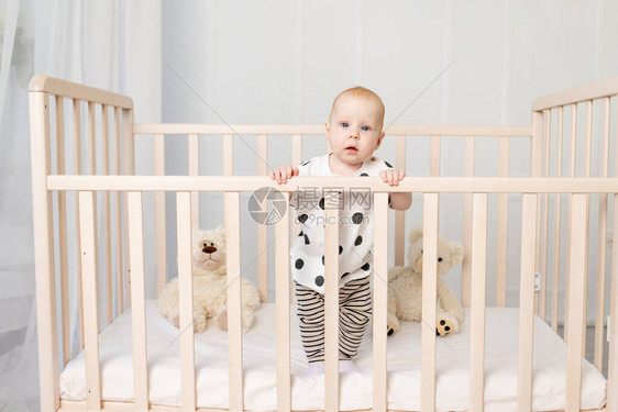 一个8个月大的婴儿睡后站在婴儿床上图片