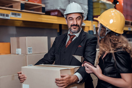 工程师妇女和商人在货物仓库中戴着安全帽站立货物图片