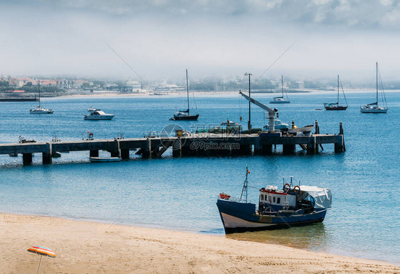 木渔船停泊在葡萄牙卡斯伊斯空荡的里贝拉海滩上在有雾的背景中几乎看不图片
