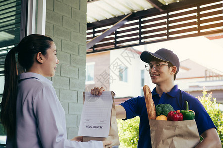 超市食品运送人员在房子门前向女顾客送上袋子图片